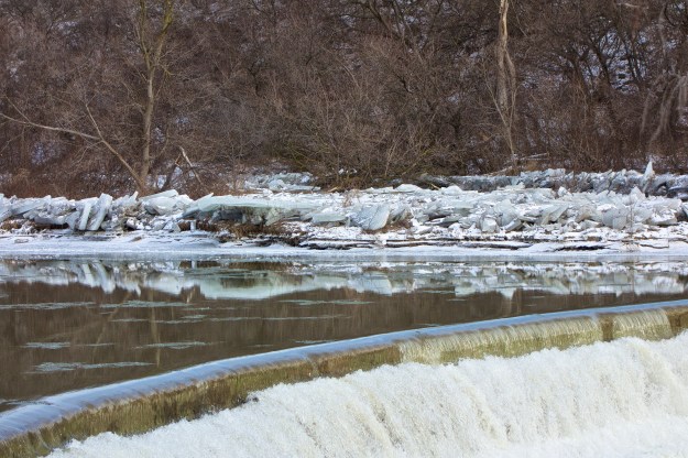 The island is covered in ice which reflects by the weir.