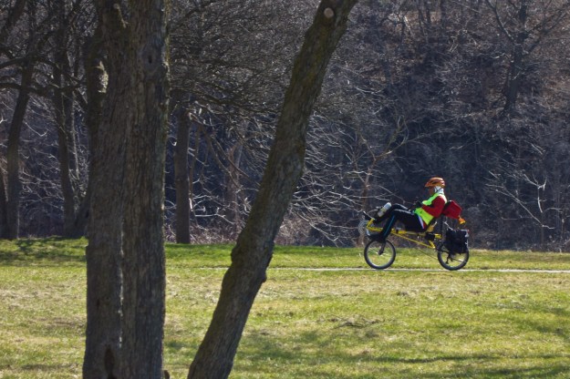 A recumbent cyclist makes his way through newly greened grass.
